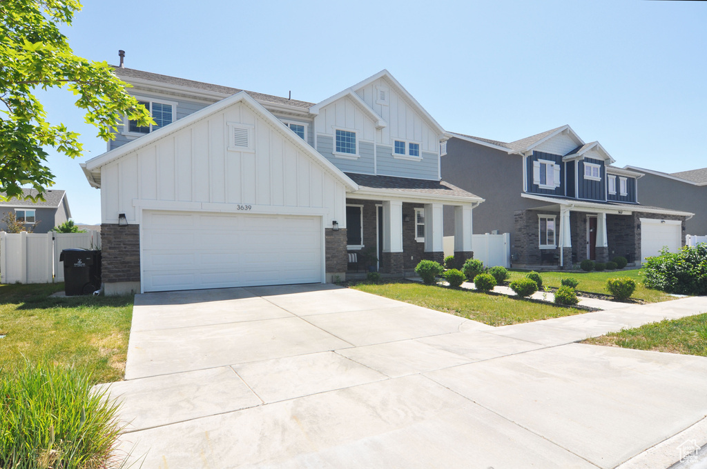 View of front of house with board and batten siding, concrete driveway, an attached garage, and stone siding
