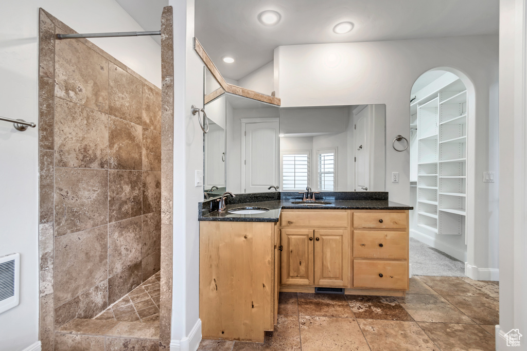 Full bath featuring a tile shower, vanity, baseboards, and a spacious closet