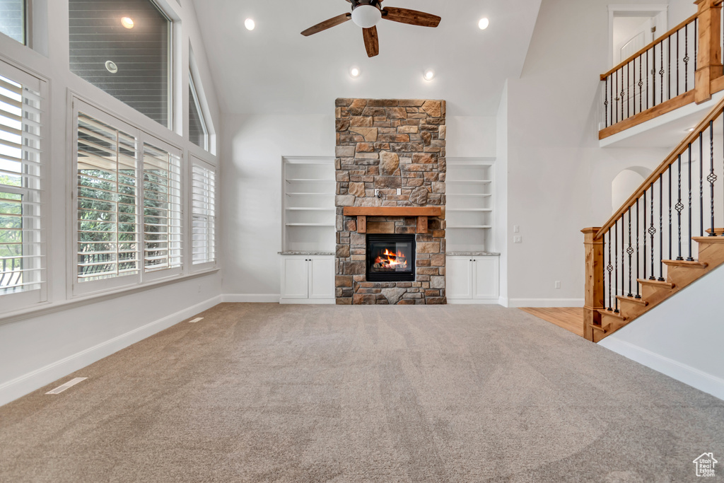 Unfurnished living room featuring carpet floors, ceiling fan, healthy amount of natural light, a towering ceiling, and recessed lighting
