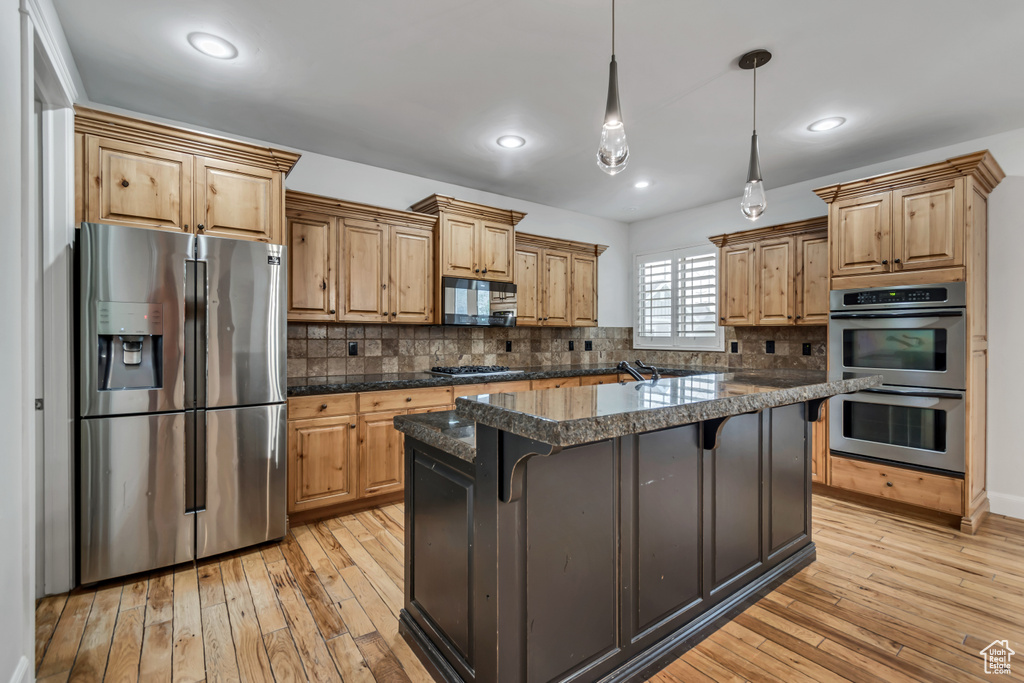Kitchen with stainless steel appliances, a kitchen bar, light wood-type flooring, backsplash, and recessed lighting