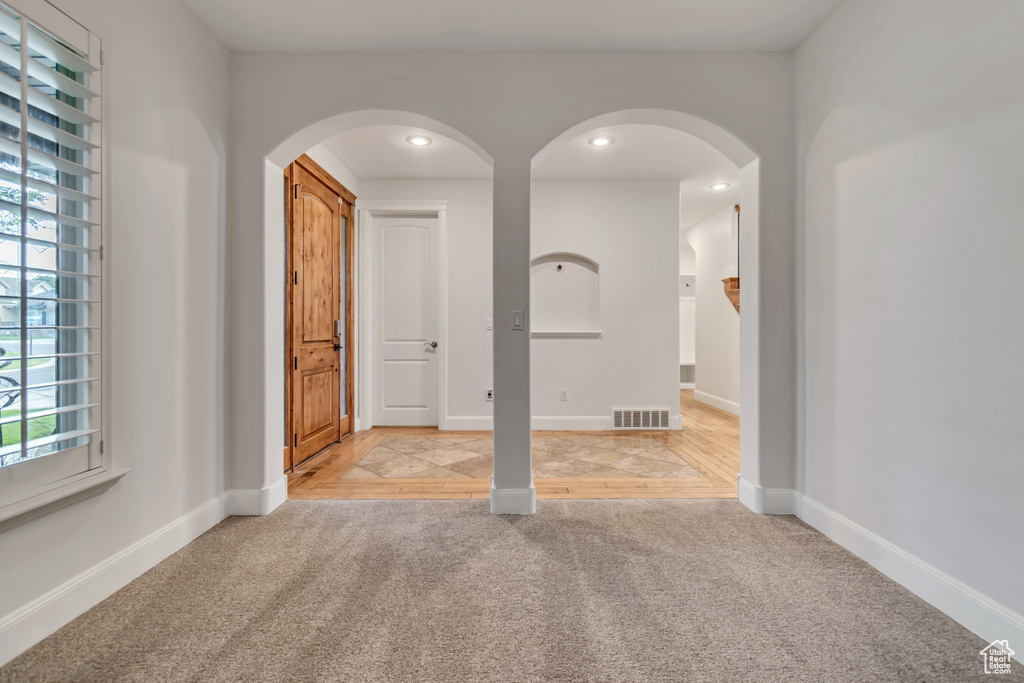 Unfurnished room with light carpet, arched walkways, baseboards, and recessed lighting