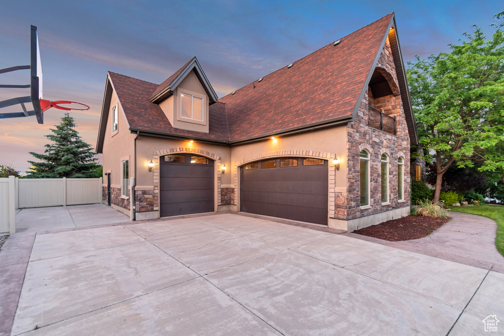 View of front of home featuring stone siding, stucco siding, driveway, a garage, and roof with shingles