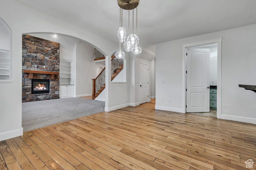 Unfurnished living room with stairway, hardwood / wood-style flooring, arched walkways, and built in features