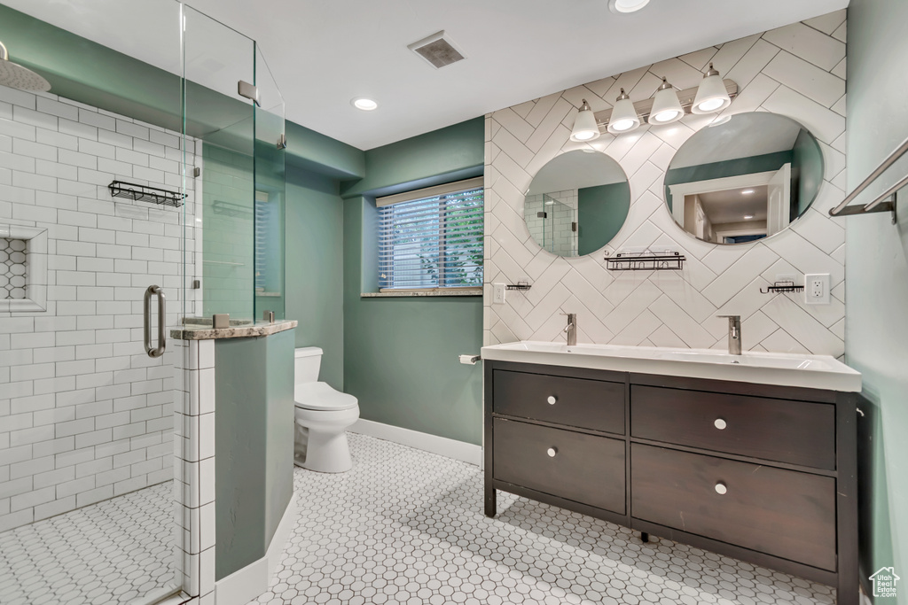 Bathroom with toilet, double vanity, a shower stall, baseboards, and tile patterned floors