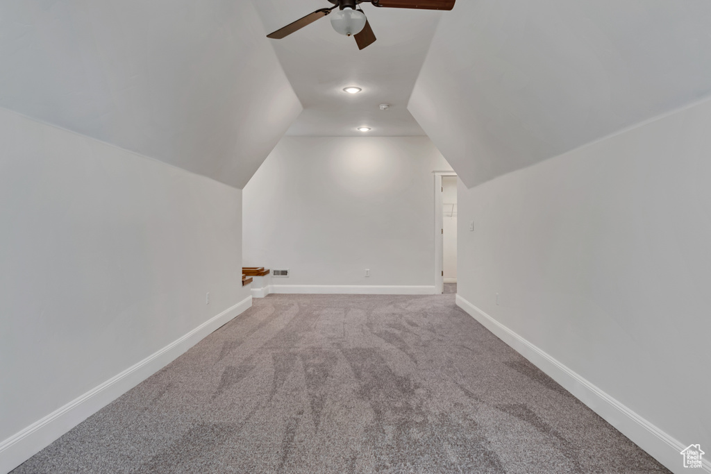 Additional living space with a ceiling fan, carpet, vaulted ceiling, and baseboards
