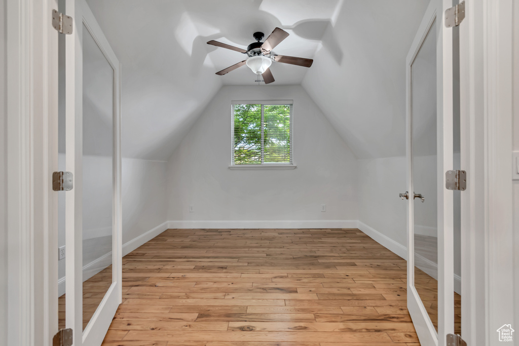 Bonus room with a ceiling fan, light wood-style floors, baseboards, and vaulted ceiling