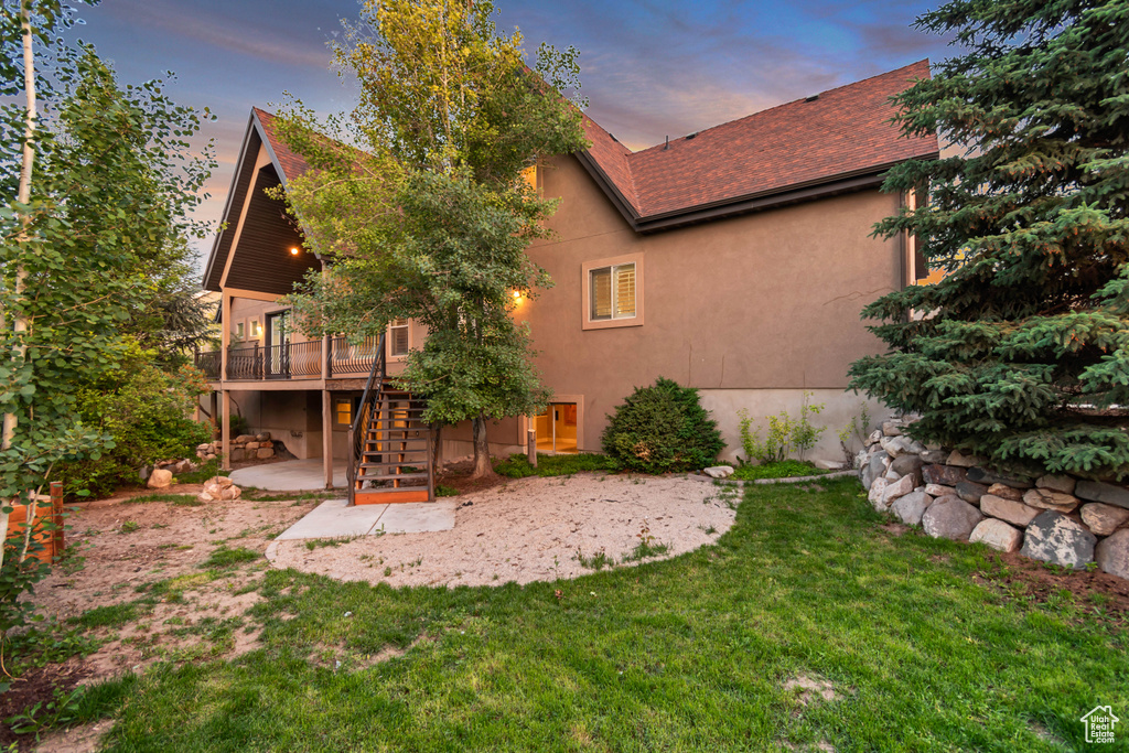 Rear view of house featuring stairs, a deck, a patio, a lawn, and stucco siding