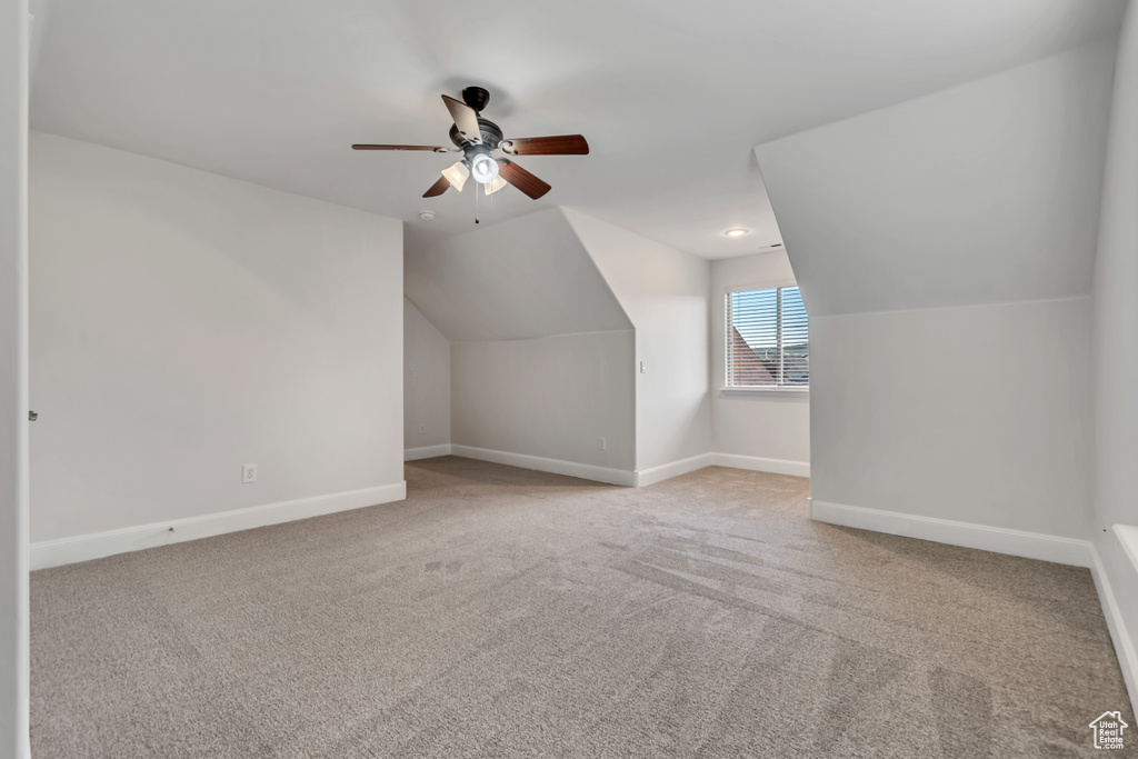 Additional living space featuring baseboards, carpet floors, lofted ceiling, and ceiling fan