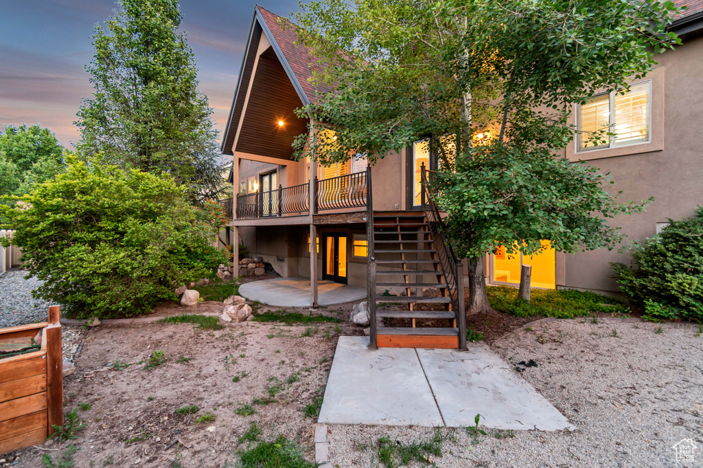 Back of property at dusk with stairway, a patio area, a wooden deck, and stucco siding
