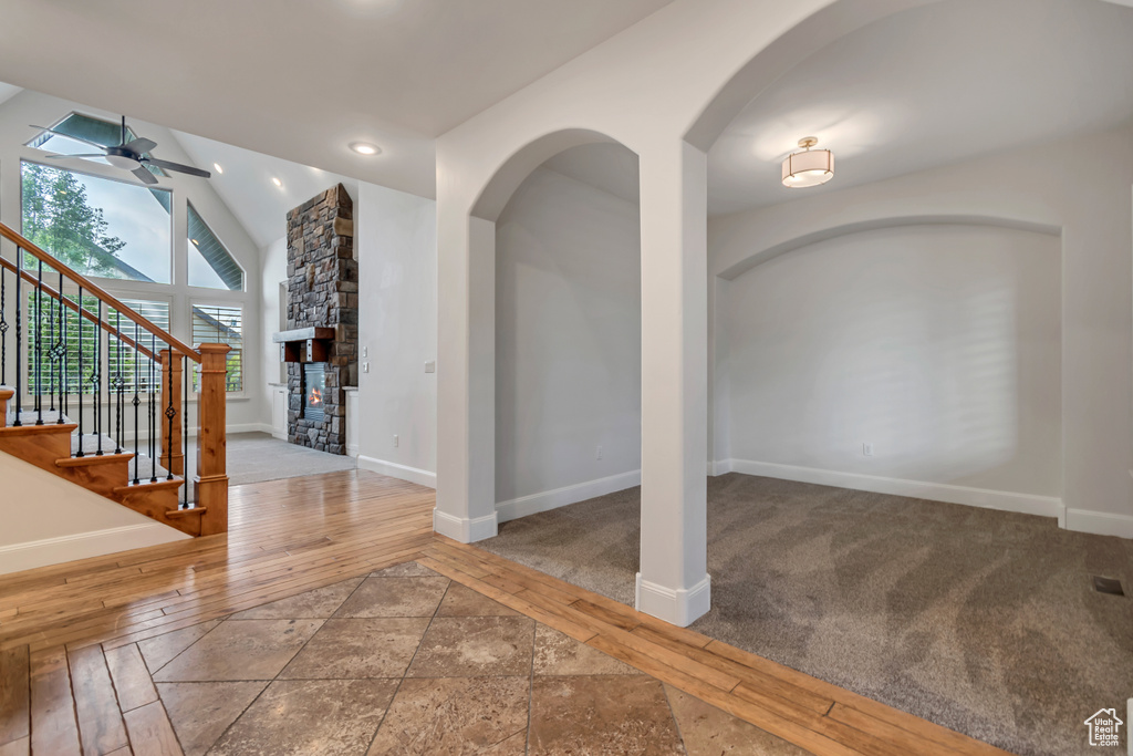 Entrance foyer featuring a ceiling fan, baseboards, arched walkways, wood-type flooring, and lofted ceiling