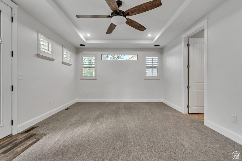 Carpeted spare room with ceiling fan, healthy amount of natural light, baseboards, a tray ceiling, and recessed lighting