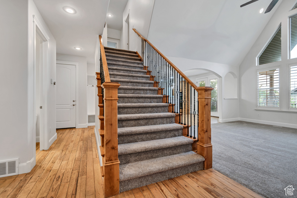 Stairway with arched walkways, hardwood / wood-style floors, baseboards, recessed lighting, and ceiling fan
