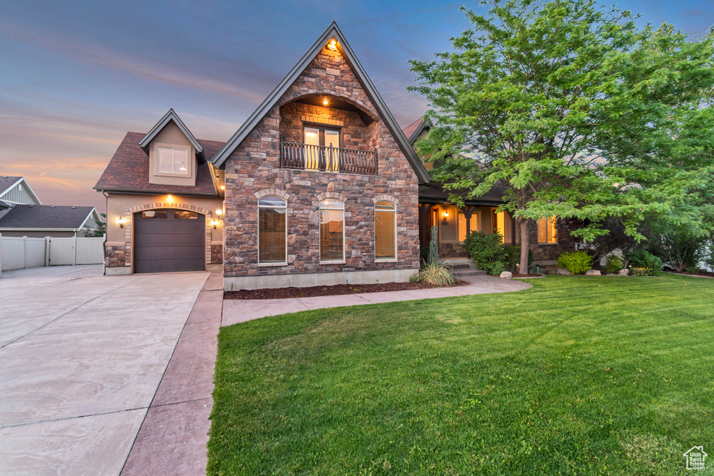 View of front facade with a balcony, driveway, and stone siding