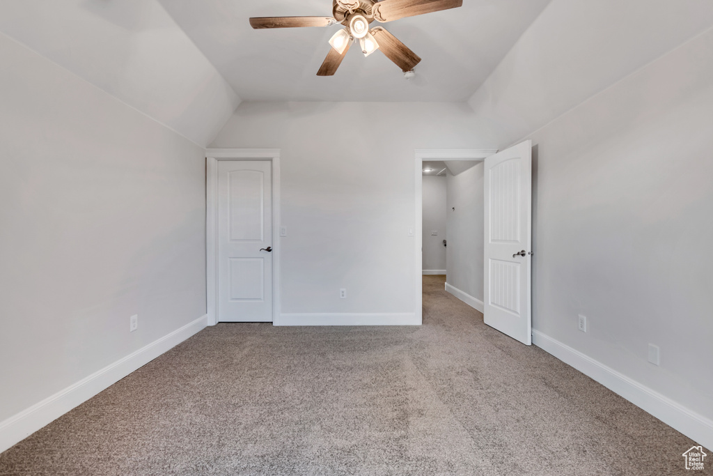 Unfurnished bedroom featuring carpet, baseboards, ceiling fan, and lofted ceiling