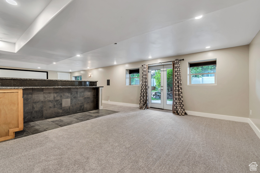 Unfurnished living room featuring baseboards, carpet floors, bar, recessed lighting, and french doors