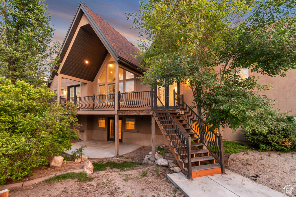 Back of property featuring a patio area, a deck, stairway, stucco siding, and french doors
