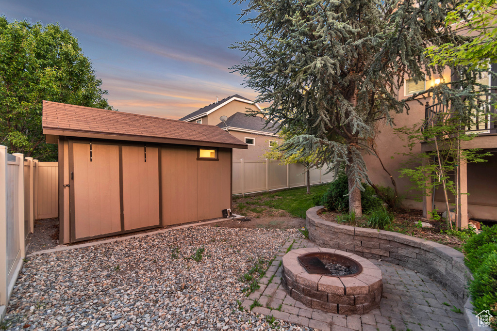 Yard at dusk with an outdoor fire pit, a fenced backyard, and a patio area