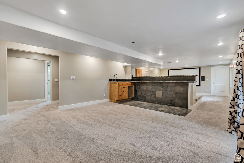 Unfurnished living room featuring wet bar, light carpet, baseboards, and recessed lighting