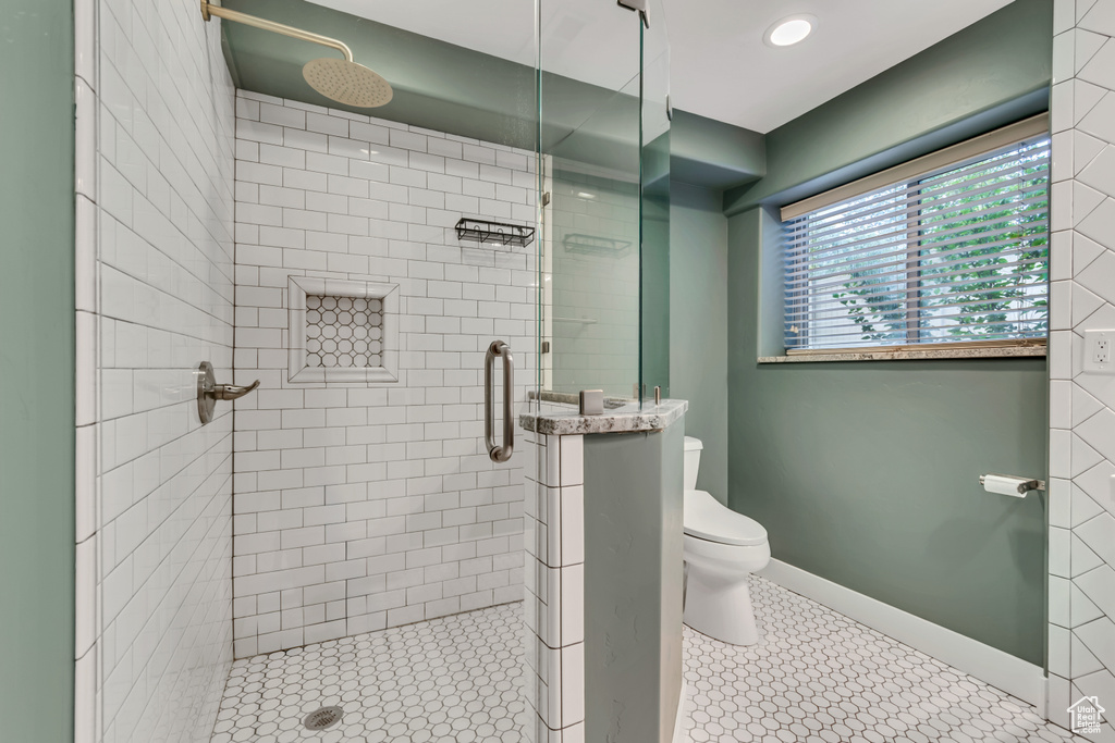 Bathroom featuring toilet, a stall shower, and baseboards
