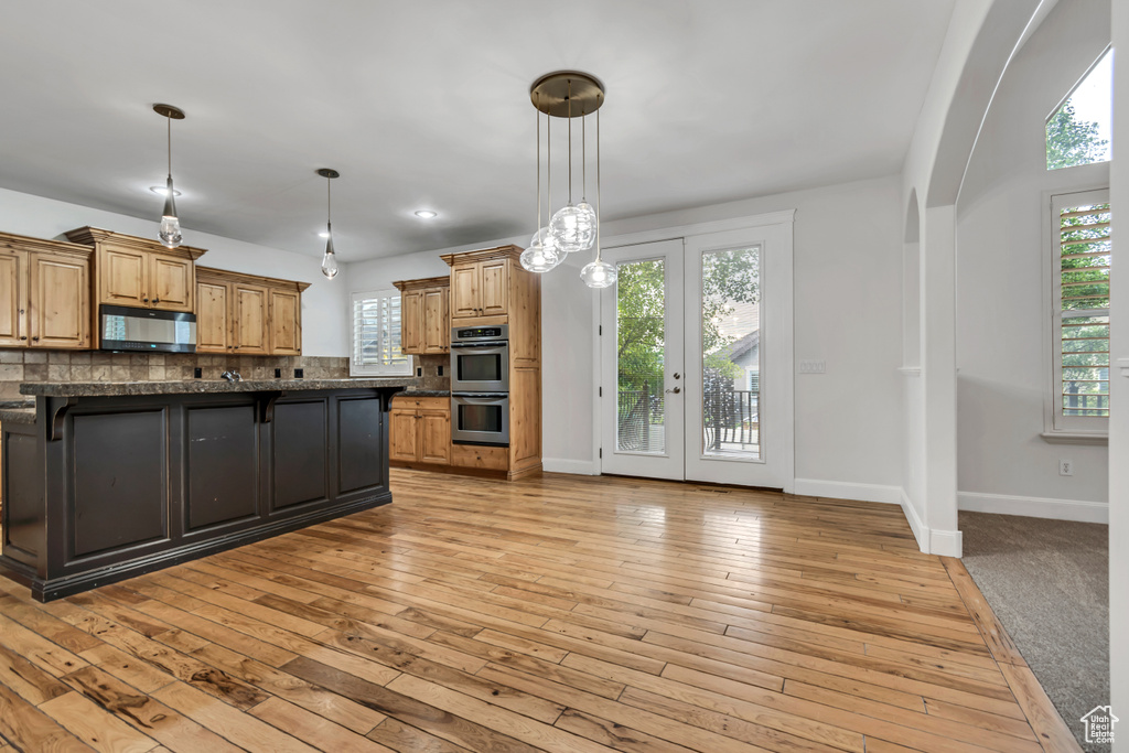 Kitchen with black microwave, double oven, a kitchen breakfast bar, decorative backsplash, and baseboards