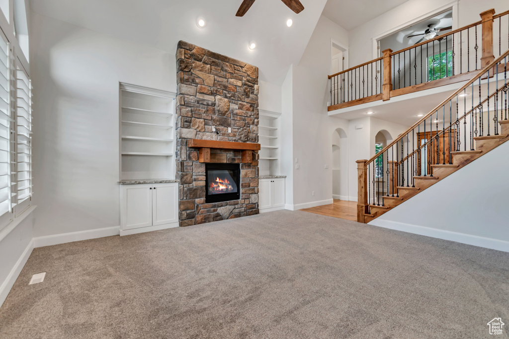 Living room featuring a ceiling fan, carpet floors, a towering ceiling, baseboards, and arched walkways