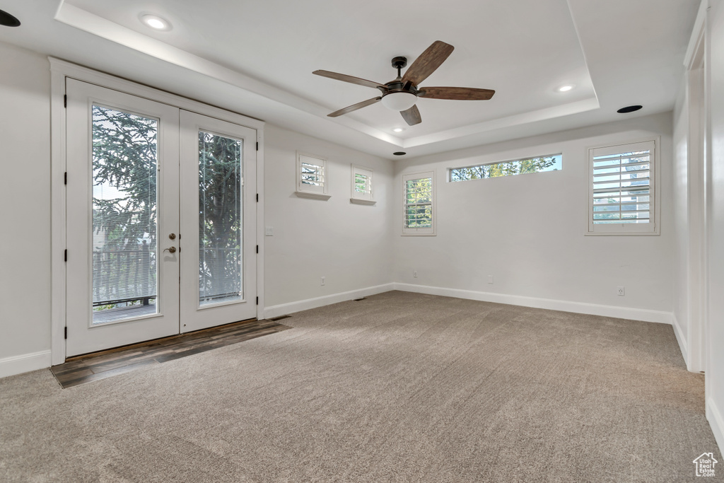 Carpeted empty room with a tray ceiling, french doors, baseboards, and recessed lighting