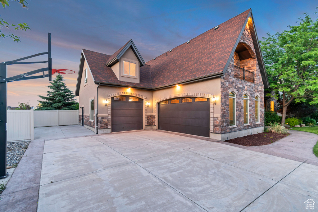 View of front of house featuring stone siding, driveway, and stucco siding