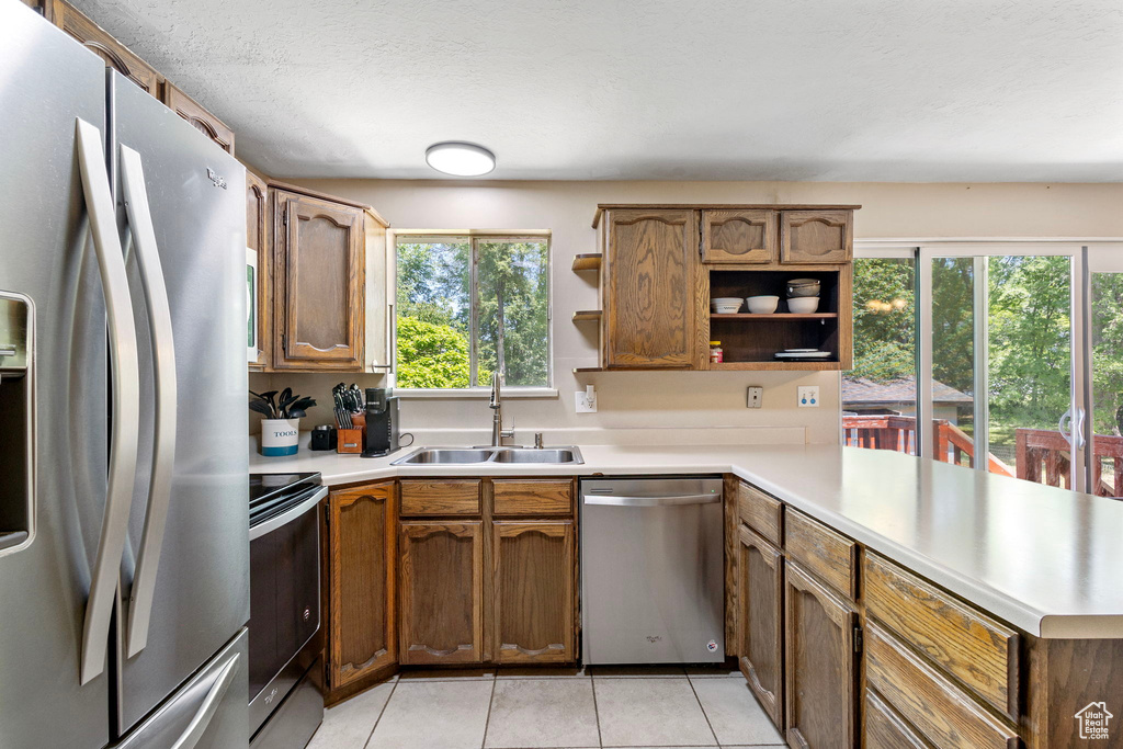 Kitchen featuring stainless steel appliances, a sink, open shelves, and light countertops
