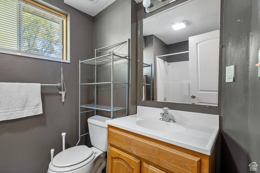 Bathroom featuring vanity, toilet, and a shower