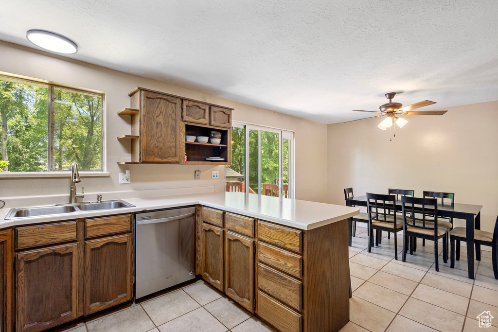 Kitchen with dishwasher, open shelves, a sink, a peninsula, and light tile patterned floors