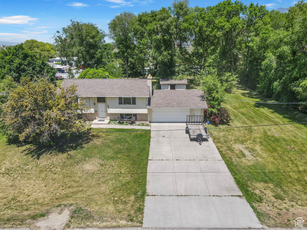 View of front of property with roof with shingles, driveway, brick siding, and a front lawn