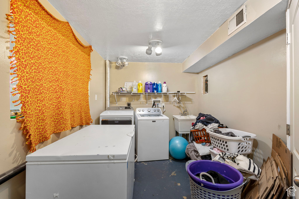 Washroom featuring washing machine and clothes dryer and a textured ceiling