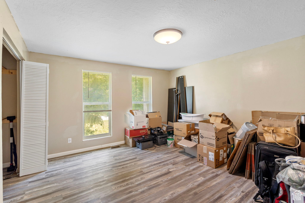 Bedroom with wood finished floors, a textured ceiling, and baseboards