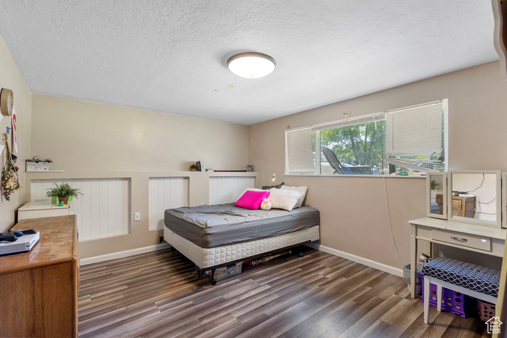 Bedroom with wood finished floors, baseboards, and a textured ceiling
