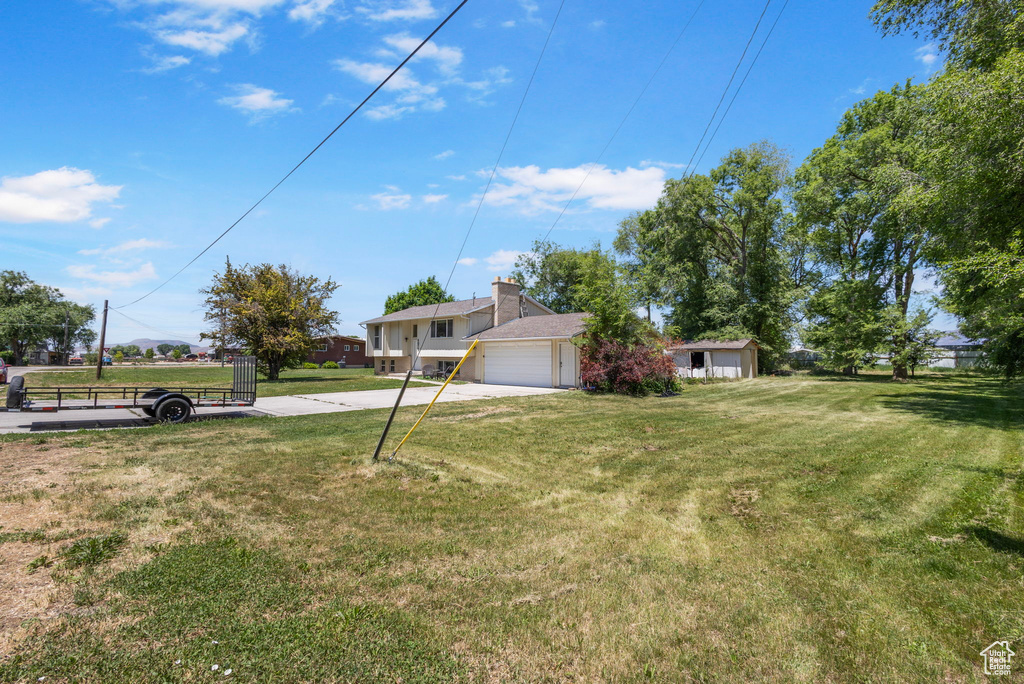 View of grassy yard with concrete driveway and a garage