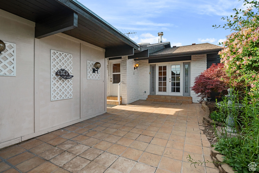 View of exterior entry with french doors, brick siding, and a patio area