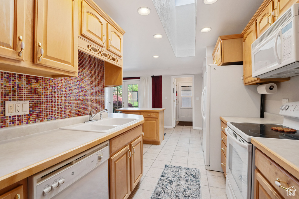 Kitchen featuring white appliances, a sink, light tile patterned floors, light brown cabinets, and recessed lighting