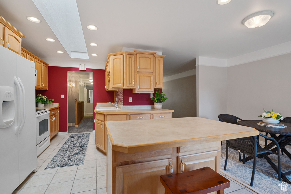 Kitchen with white appliances, light brown cabinetry, a sink, light countertops, and recessed lighting