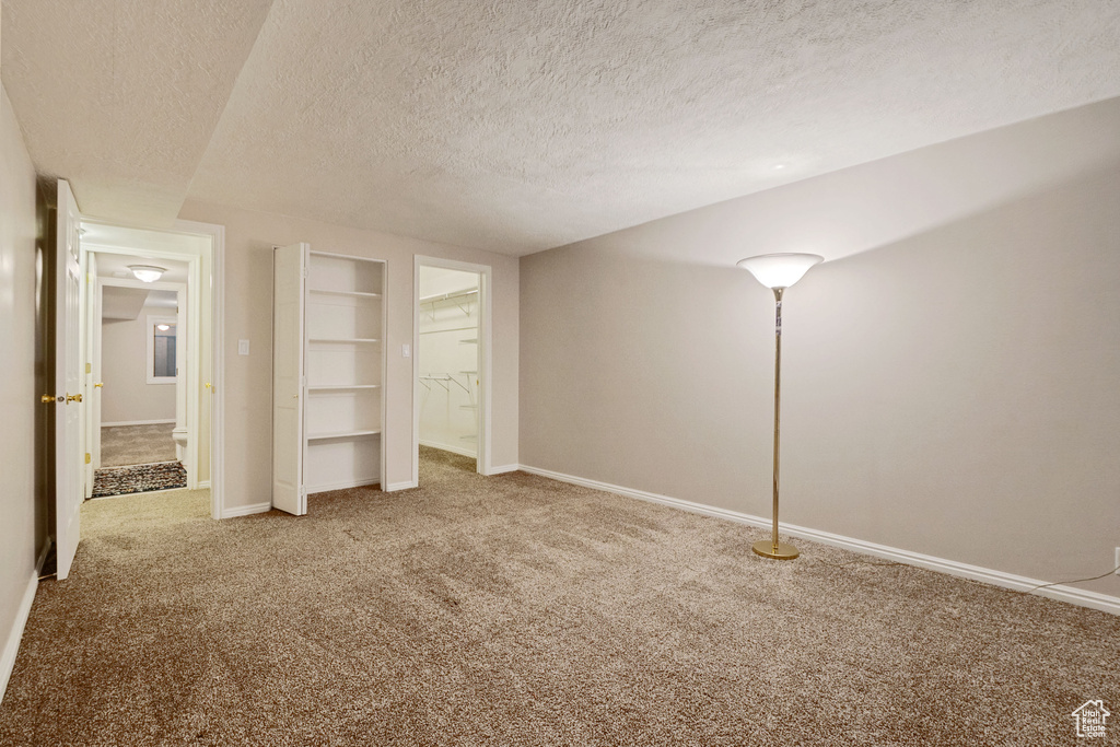 Unfurnished bedroom with carpet flooring, a textured ceiling, and baseboards