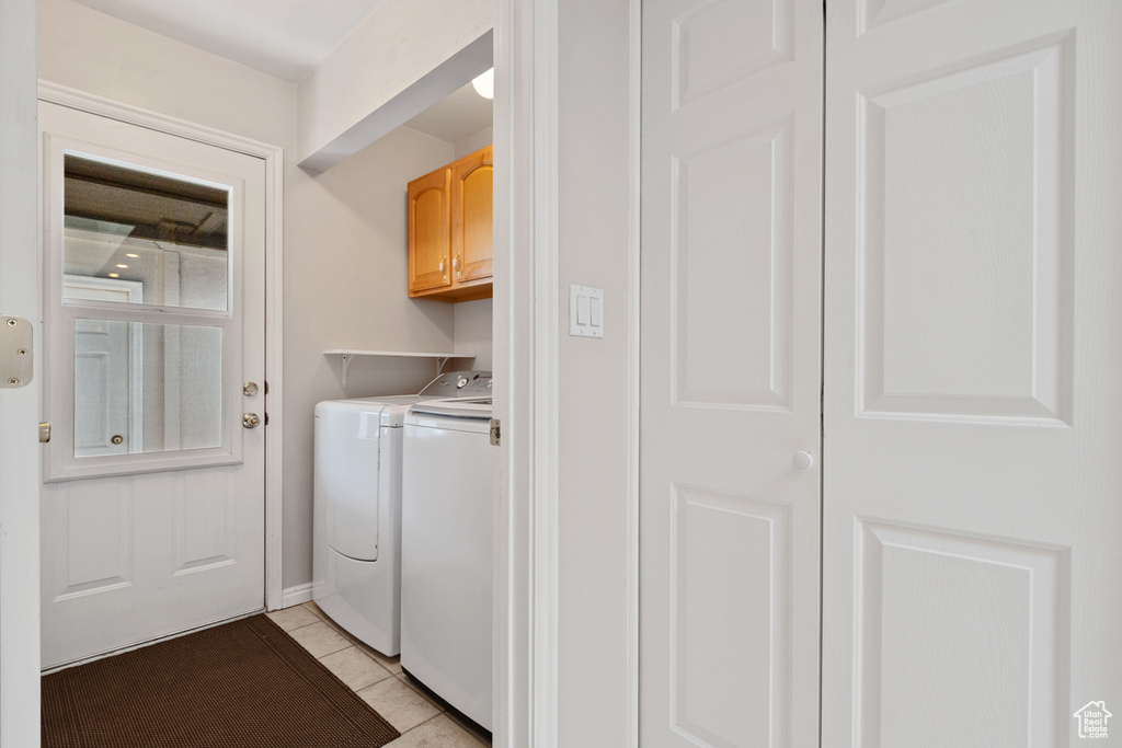 Washroom featuring cabinet space, independent washer and dryer, and light tile patterned floors