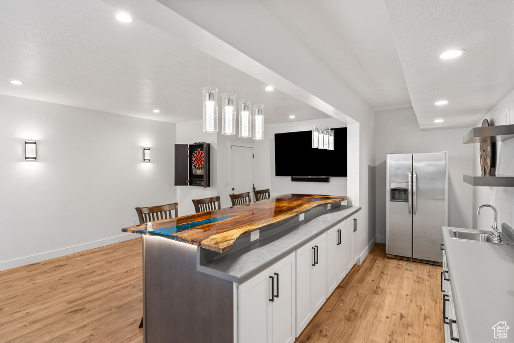 Kitchen with stainless steel fridge, a sink, light wood-style flooring, recessed lighting, and white cabinets