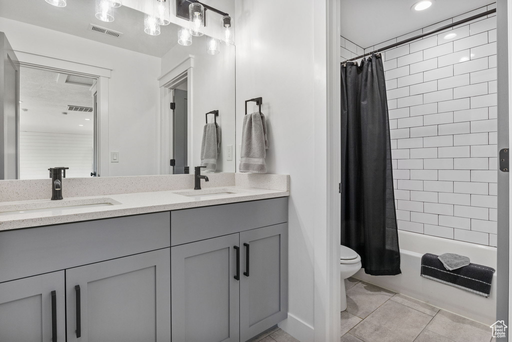Full bath with double vanity, toilet, shower / bath combo, and tile patterned flooring