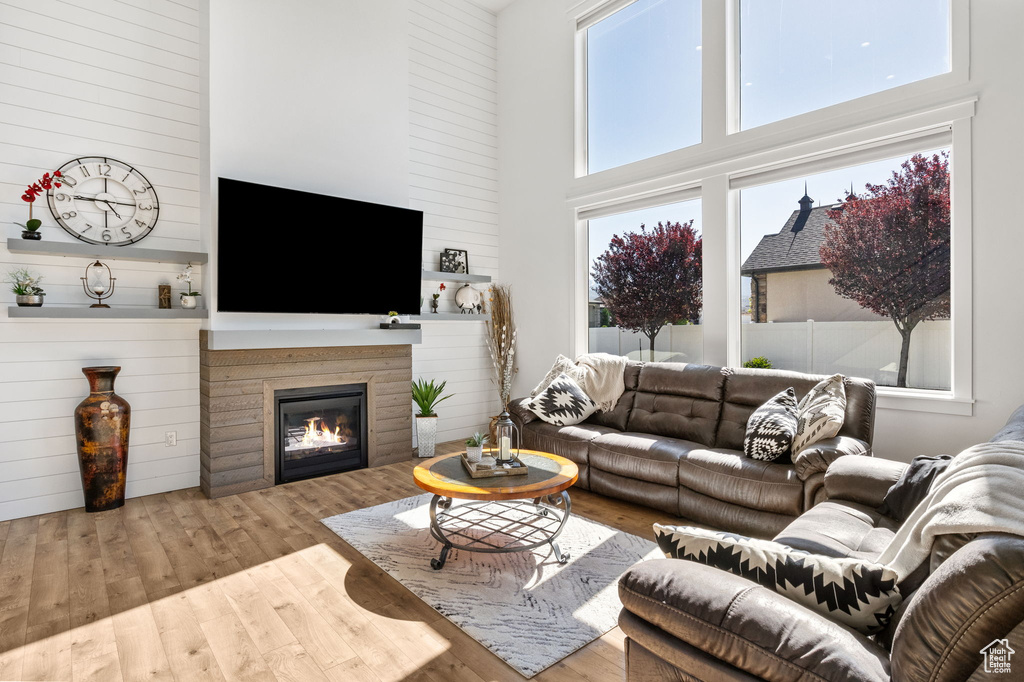 Living area with a high ceiling, wood finished floors, and a glass covered fireplace