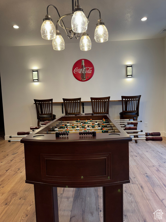 Game room featuring baseboards, light wood finished floors, recessed lighting, and a chandelier