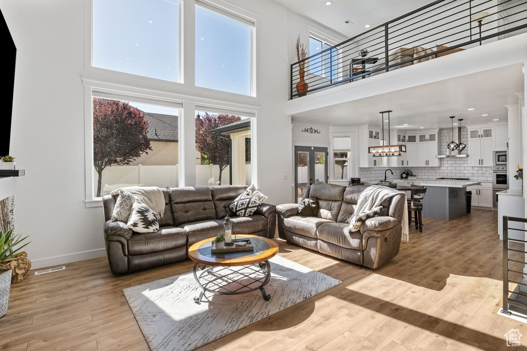 Living area featuring a towering ceiling, light wood-type flooring, recessed lighting, and baseboards