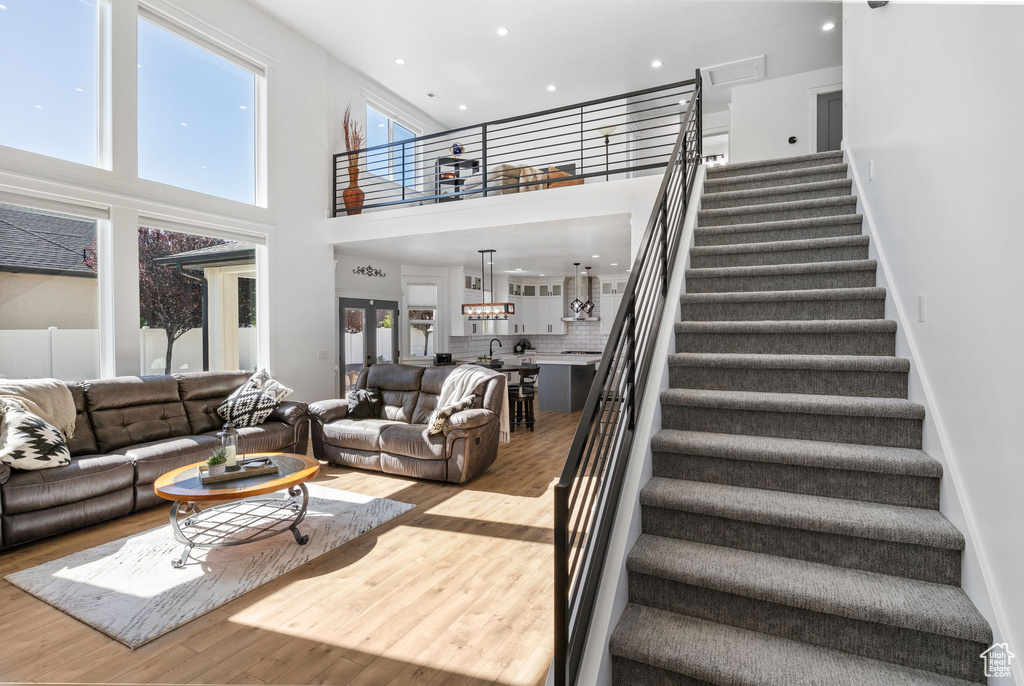 Living room featuring a high ceiling, wood finished floors, stairs, and recessed lighting