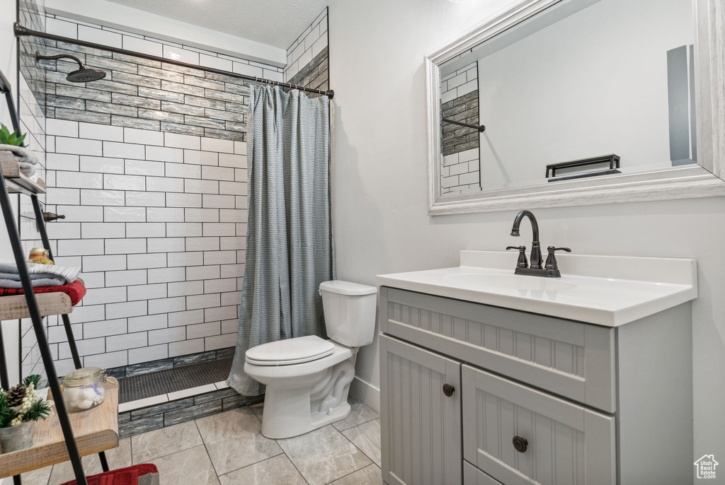 Bathroom featuring tiled shower, vanity, and toilet
