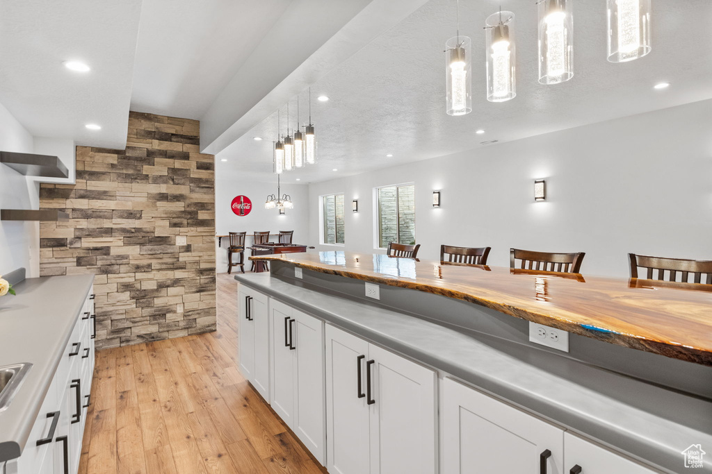 Kitchen with recessed lighting, pendant lighting, light wood finished floors, white cabinetry, and a chandelier