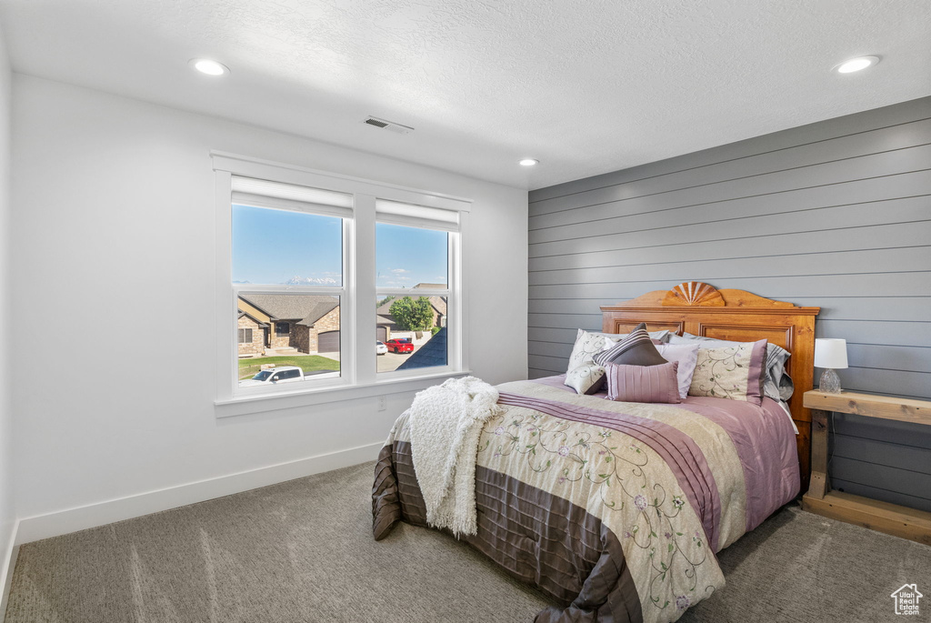 Carpeted bedroom with baseboards, recessed lighting, a textured ceiling, and wooden walls