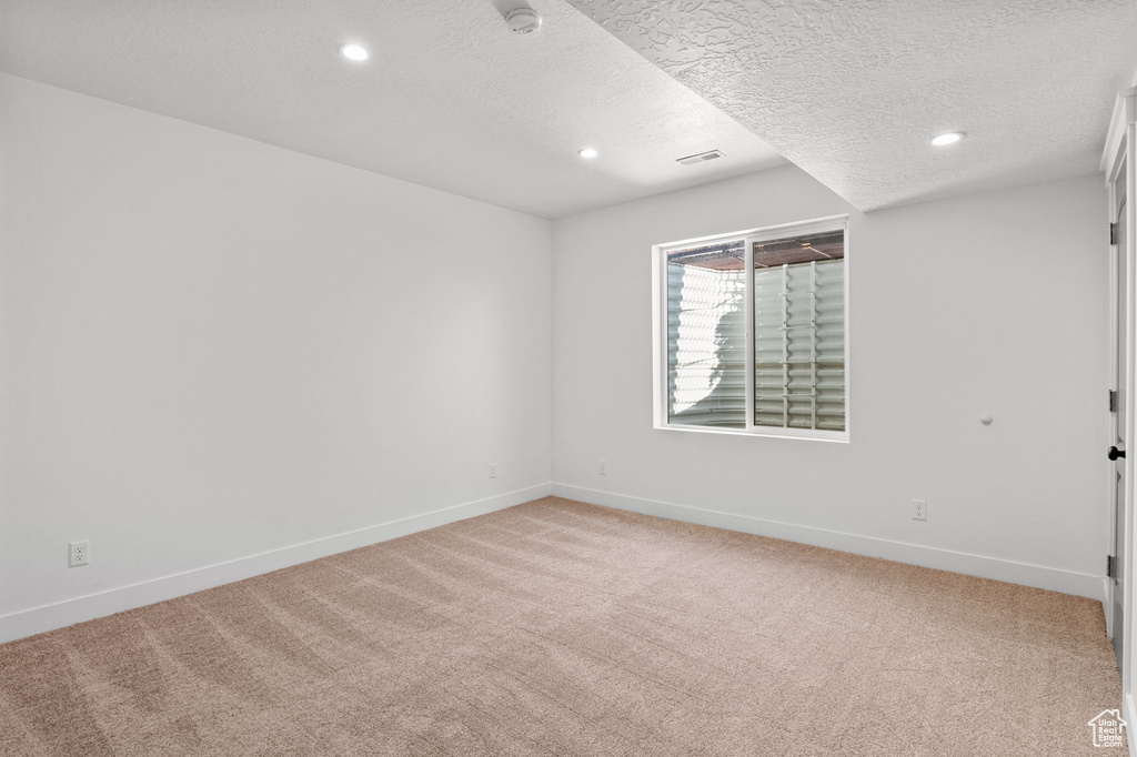 Empty room featuring light carpet, recessed lighting, baseboards, a textured ceiling, and a smoke detector